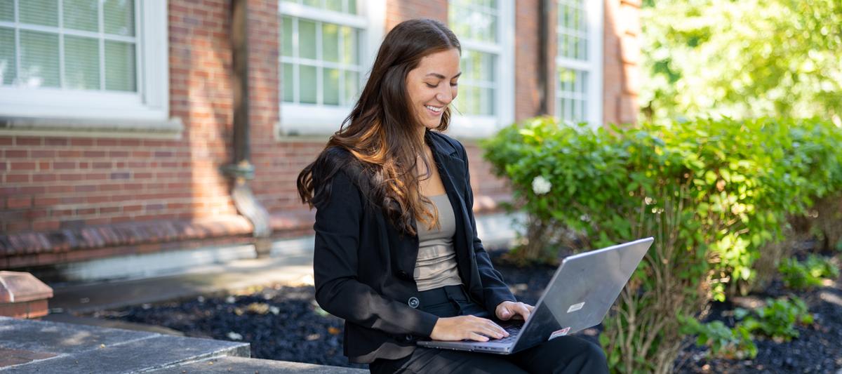 Student sitting with their laptop outside